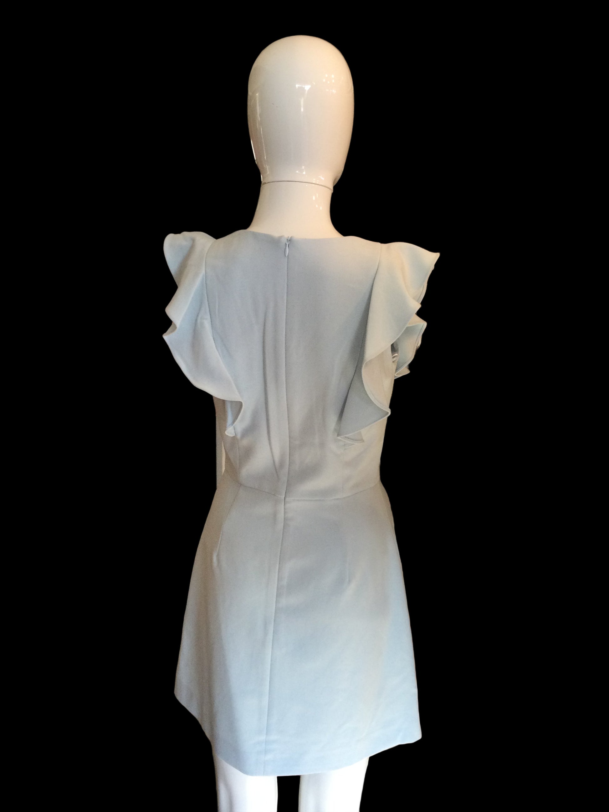 Mannequin wearing a light blue dress with a blurred background of clothing racks.